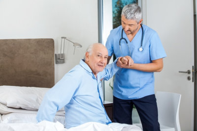 senior man being assisted by male caregiver